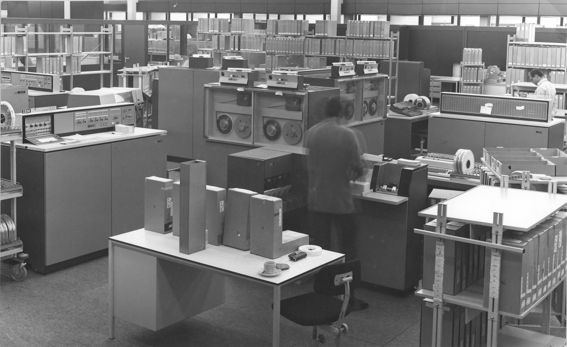 Grote zaal met apparatuur waar man met IBM 360-20 werkt